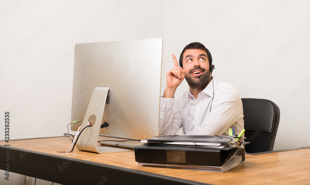 Telemarketer man in a office pointing a great idea and looking up Telemarketer man in a office pointing a great idea and looking up