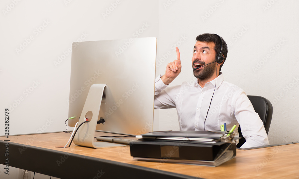 Telemarketer man in a office intending to realizes the solution while lifting a finger up Telemarketer man in a office intending to realizes the solution while lifting a finger up