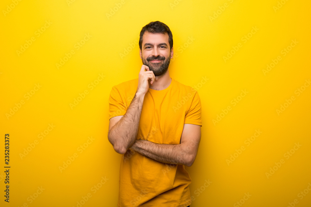 Man on isolated vibrant yellow color smiling with a sweet expression Man on isolated vibrant yellow color smiling with a sweet expression