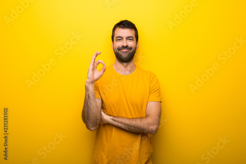 Man on isolated vibrant yellow color showing an ok sign with fingers