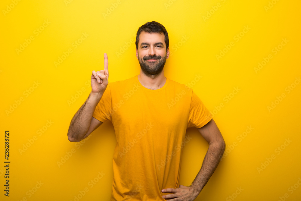 Man on isolated vibrant yellow color showing and lifting a finger in sign of the best Man on isolated vibrant yellow color showing and lifting a finger in sign of the best