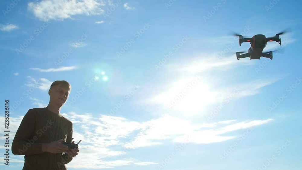Concept of personal drones and aerial photography. Young man with a quadrocopter remote control Concept of personal drones and aerial photography. Young man with a quadrocopter remote control