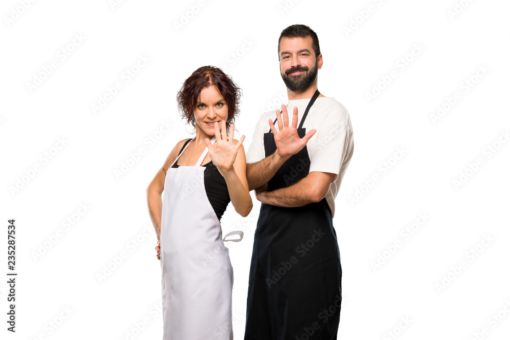 Couple of cooks counting five with fingers on isolated white background Couple of cooks counting five with fingers on isolated white background