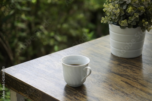 White cup of black coffee on the wooden table in the morning