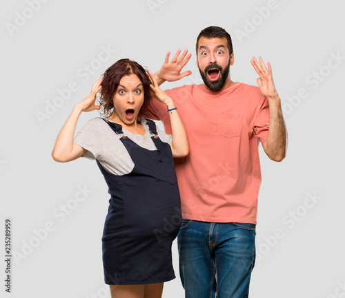 Couple with pregnant woman with surprise and shocked facial expression on isolated grey background
