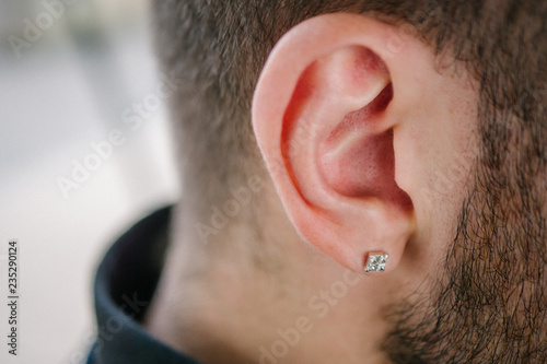 Earring in the male ear. Piercing Part of the body.