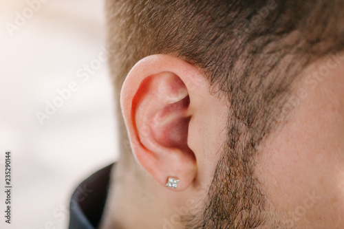 Earring in the male ear. Piercing Part of the body.