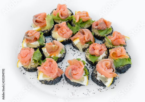 Close up of small canapes arranged on a plate over light background - selective focus