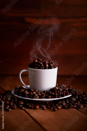 A white cup full of hot coffee beans on a wooden table
