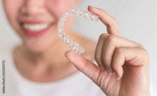 A smiling woman holding invisalign or invisible braces, orthodontic equipment photo