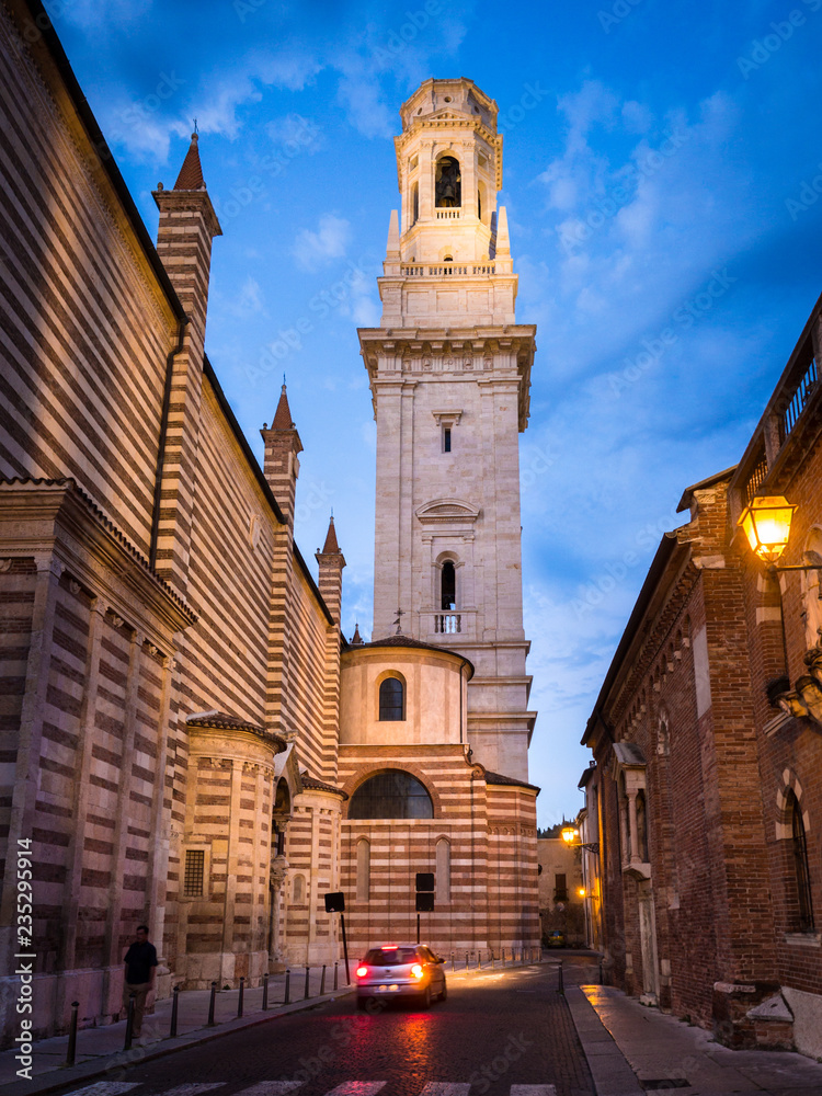 The white bell tower of the Verona Cathedral in Italy at sunset.