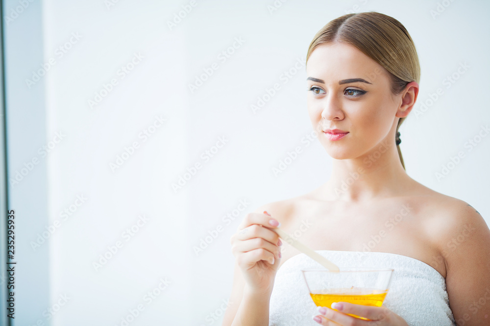 Women hold orange paraffin wax bowl. Woman in beauty salon Women hold orange paraffin wax bowl. Woman in beauty salon
