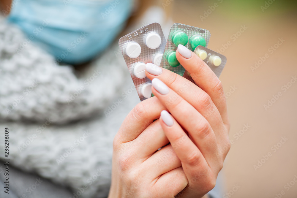 Cold and flu. Woman in autumn park holding pills Cold and flu. Woman in autumn park holding pills