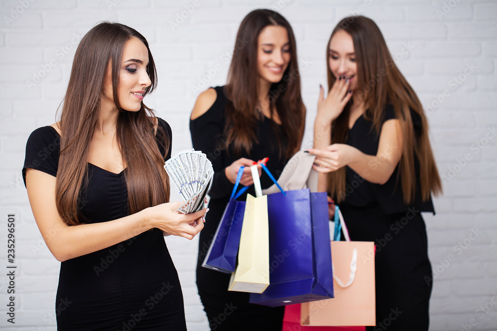 Shopping. Three women holding colored bags on light background in black friday holiday