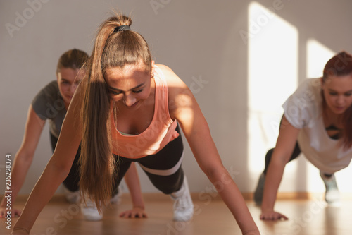 Young positive women exercising in fitness class. Beautiful females doing push ups exercise