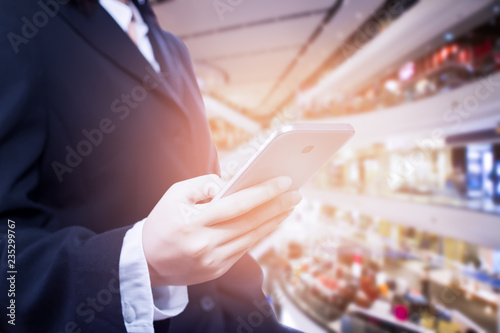 Asian business woman using smart phone on blurred shopping mall background