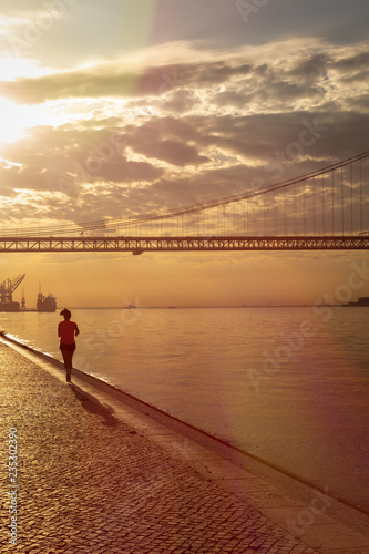 Silhouette of a young woman running down the pier. A huge traffic bridge. © Horacio Selva