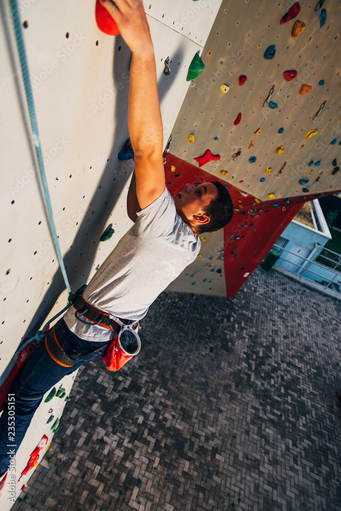 Sportive man climbs up on artificial rock wall Sportive man climbs up on artificial rock wall