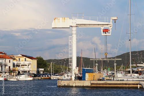 Crane lift for raising boats in the marina ACI Jazera in Croatia. Dalmatian ragion of Adriatic sea at Mediterranean area. The ships moored in the port of a quiet fishing town in a sunny,clear day. photo