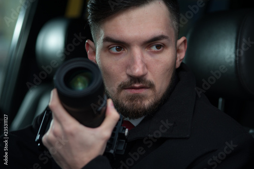 Young Male Photographer Takes A Camera With A Zoom Lens And Takes Pictures. Concept Of Espionage And Photography