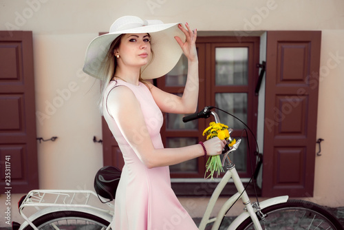 beautiful girl in a pink dress with flowers on a bicycle. portrait