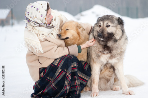 Woman trains Caucasian Shepherd and yard dog on a snowy ground in the park photo