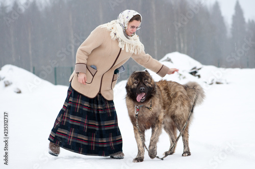 Woman trains Caucasian Shepherd and yard dog on a snowy ground in the park photo