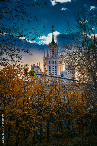 View of the Stalinist skyscraper through the autumn trees at sunset