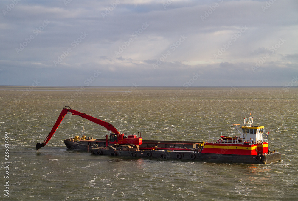 Red dredging vessel working on sea, removing sediment in a waterway Red dredging vessel working on sea, removing sediment in a waterway