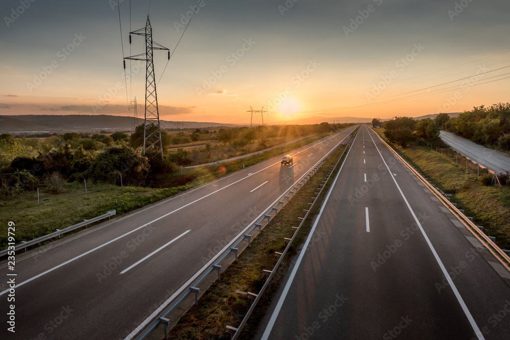 Single Car at a Beautiful Silent Countryside Motorway and power line at sunset