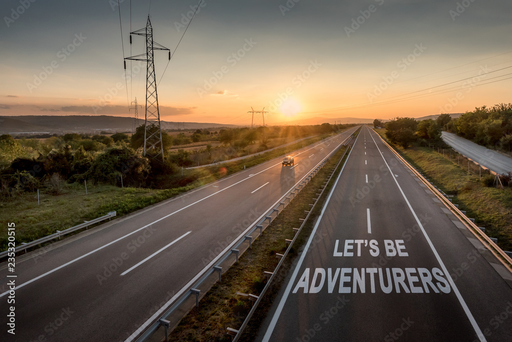 Beautiful Countryside Motorway with a Single Car at sunset with motivational message Let's Be Adventureus Beautiful Countryside Motorway with a Single Car at sunset with motivational message Let's Be Adventureus