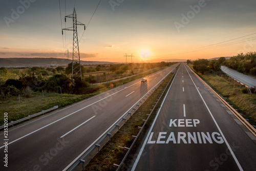 Beautiful Countryside Motorway with a Single Car at sunset with motivational message Keep Learning