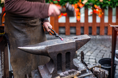 A blacksmith hammering a red hot horse nail at s Czech Christmas market in Prague  - 1 photo