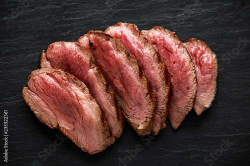 Medium rare venison steak on rustic dark stone board Fototapeta