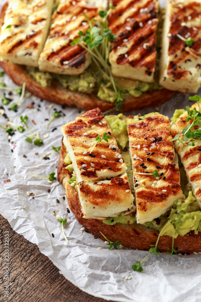 Avocado and grilled haloumi cheese toast with nigella and sesame seeds on crumpled paper. healthy breakfast