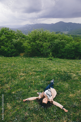 Woman lying on grass in meadow with eyes closed.