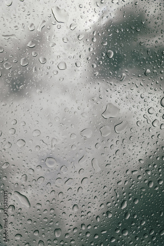 Glass with water drops under the heavy cloudy sky.