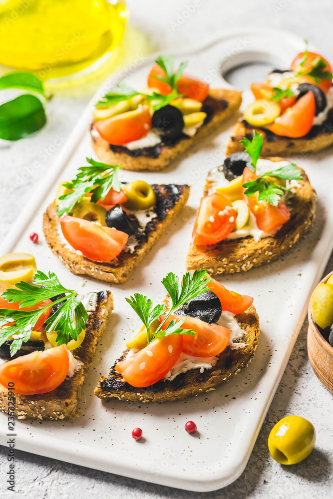 Olives cherry tomatoes goat cheese bruschetta. Selective focus, space for text. Olives cherry tomatoes goat cheese bruschetta. Selective focus, space for text.