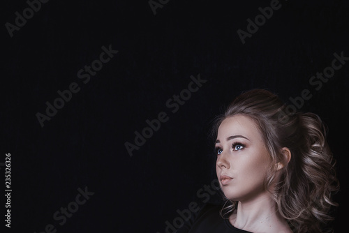 beautiful blonde girl looking sideways on black background copy space