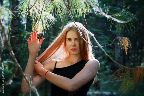 Obraz na płótnie Beautiful girl with long hair poses with a cedar cone in the Siberian taiga w salonie