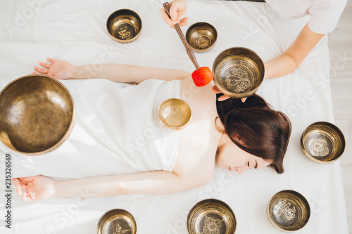 Girl doing massage therapy singing bowls in the Spa