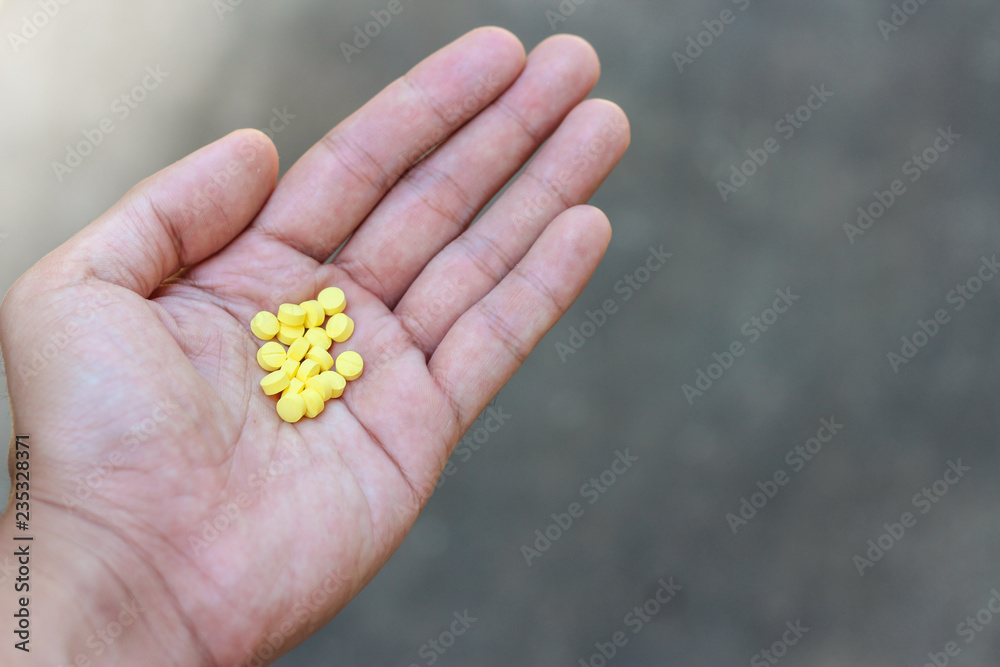Yellow pills in hand on background. Yellow pills in hand on background.