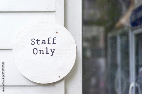 Staff only sign on wooden white door and kitchen entrance, inside workplace.