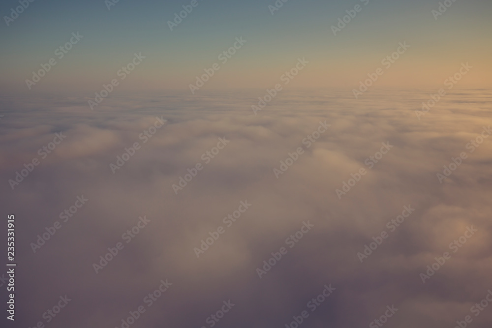 Layer of clouds taken from aircraft above scene illuminated by low evening or morning sun rays of warm golden color. Easy background photography of simple composition and empty space.
