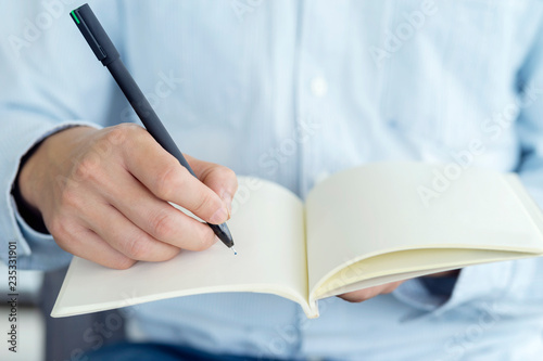 Close up hand of businessman holding pen and notebook, Writing something idea on note or check list.