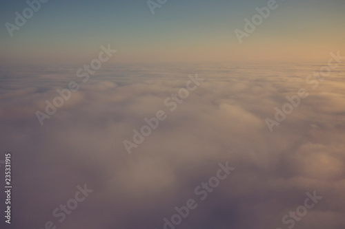 Layer of clouds taken from aircraft above scene illuminated by low evening or morning sun rays of warm golden color. Easy background photography of simple composition and empty space.