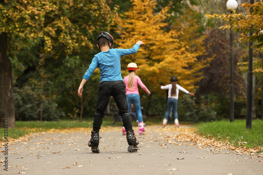 Cute children roller skating in autumn park Cute children roller skating in autumn park
