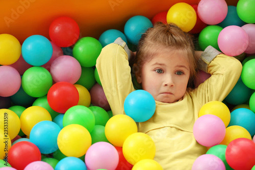 Cute little child playing in ball pit at indoor amusement park