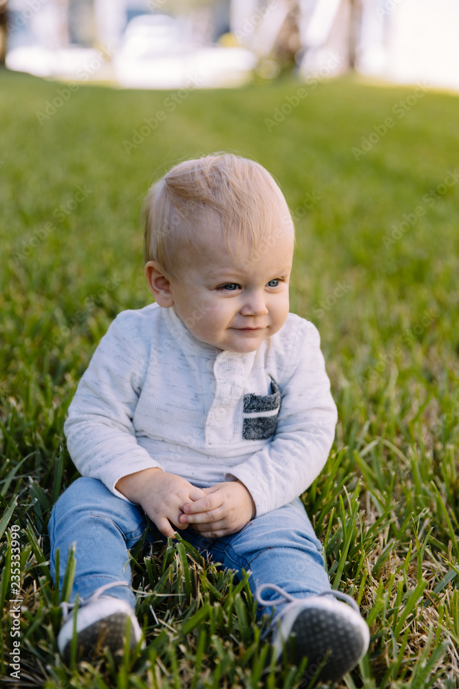 Cute and Adorable Young Toddler Baby Boy Playing in the Backyard Green Grass and Smiling at the Camera Cute and Adorable Young Toddler Baby Boy Playing in the Backyard Green Grass and Smiling at the Camera