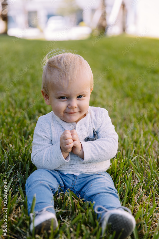 Cute and Adorable Young Toddler Baby Boy Playing in the Backyard Green Grass and Smiling at the Camera Cute and Adorable Young Toddler Baby Boy Playing in the Backyard Green Grass and Smiling at the Camera